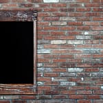 A wall of brick with a wooden framed window.
